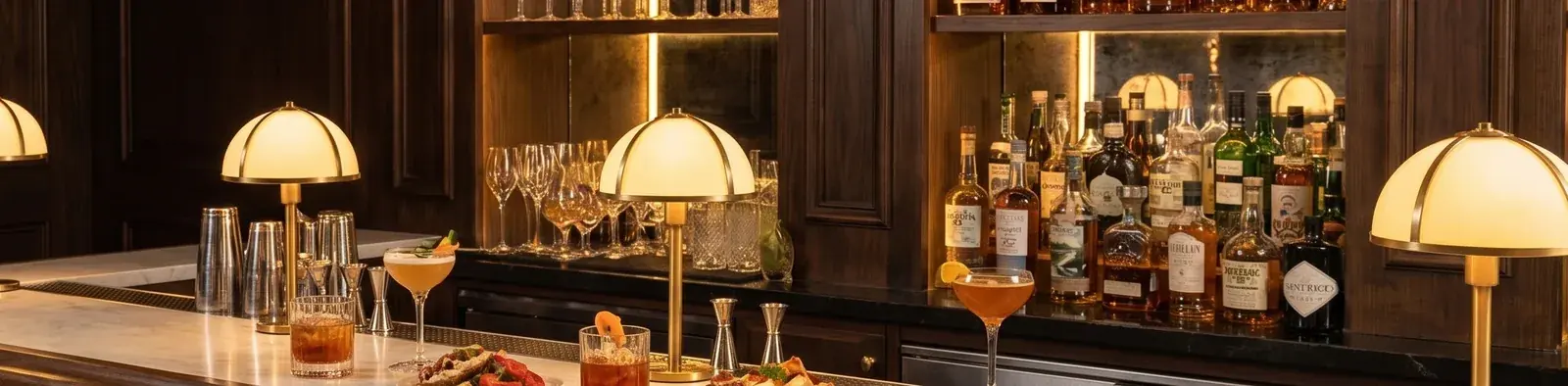 Barra de latón de Terra & Mar Bistró con cócteles de autor y aperitivos servidos, botellería al fondo